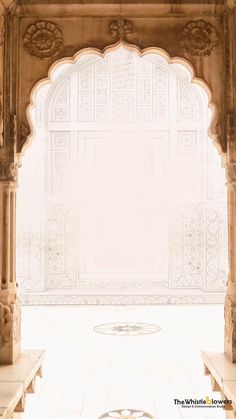 an archway in the middle of a building with white walls and carvings on each side