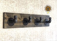 a wooden coat rack with four black knobs and two hooks on the side, hanging from a wall