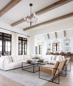 a living room filled with white furniture and wooden beam ceiling beams in an open floor plan