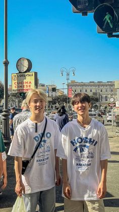 two young men standing next to each other under a traffic light