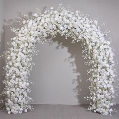 a white flowered arch is set up against a wall in the shape of a heart