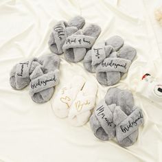 six pairs of slippers with names on them sitting on a white sheet next to a bottle of milk