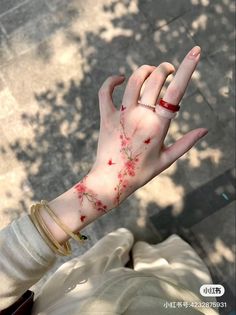 a woman's hand with red flowers painted on it and her fingers extended out