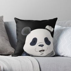 a black and white panda bear pillow sitting on top of a gray couch next to pillows