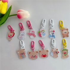 several different colored bear shaped key chains next to a tulip with flowers in the background