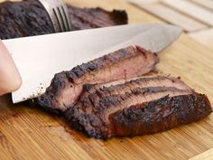 someone is cutting up some meat on a wooden board