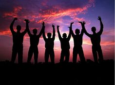 silhouettes of people with their hands up in the air at sunset or dawn,