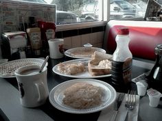 two white plates topped with food next to a cup of coffee and a bottle of milk