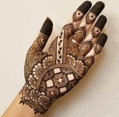 a henna tattoo on someone's hand that is decorated with geometric designs and shapes