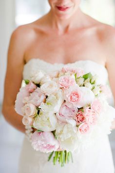 a bride holding a bouquet of pink and white flowers