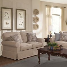 a living room with two couches, a coffee table and pictures on the wall