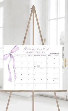 an easel with a baby's name on it and a purple ribbon hanging from the