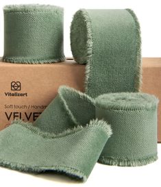 two rolls of green velvet ribbon in front of a cardboard box