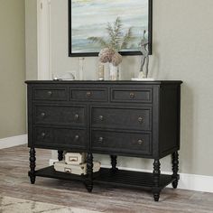 a black dresser with two vases on top and a painting above it in a living room