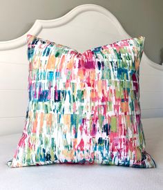 a colorful pillow sitting on top of a white bed