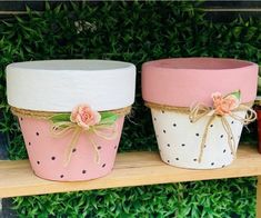 three flower pots are sitting on a shelf next to each other, one is painted pink and the other is white