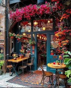 an outdoor cafe with flowers hanging from the ceiling and tables set up in front of it