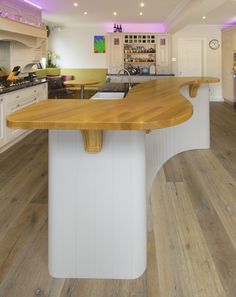 a large kitchen with an island in the middle and wooden flooring on the other side