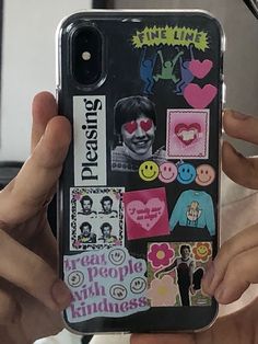 someone holding up their cell phone with some stickers on it's back cover