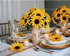 the table is set with sunflowers in vases and place settings for dinner