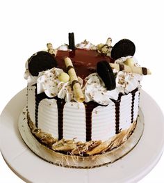 an oreo cookie and cream cake on a white plate with chocolate frosting, marshmallows, and sprinkles