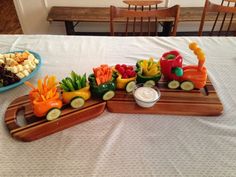 a table topped with two trays filled with vegetables and veggies next to a bowl of dip