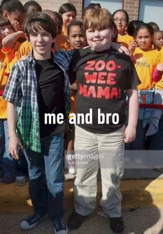 two young boys standing next to each other in front of a group of children wearing yellow shirts