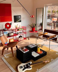 a living room filled with furniture and a guitar on top of a rug in front of a window