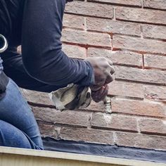 a man is painting the side of a brick building