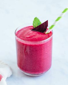 a smoothie in a glass with a green and white straw sticking out of it