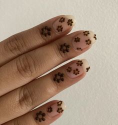 a woman's hand with brown and black flowers on her nails, holding onto the tip of her nail