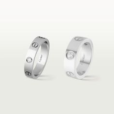 two white gold wedding bands with diamonds on each side and the word love written in silver