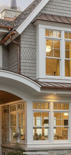 a cat sitting on top of a wooden bench in front of a large house with windows