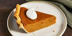 a slice of pumpkin pie on a plate with a dollop of whipped cream in the middle