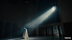 a woman is standing in the dark with light coming from behind her and she is wearing a long white dress