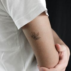 a woman holding her arm with a tattoo on it's left arm and the other arm behind her