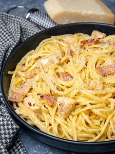 chicken and bacon pasta in a skillet ready to be eaten with bread on the side