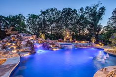 an outdoor swimming pool surrounded by rocks and lights