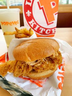 a chicken sandwich and french fries are sitting on a table next to a cup of soda