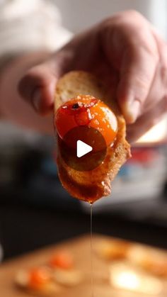 a person holding a piece of bread with jelly on it and drizzled with ketchup