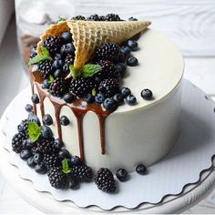 an ice cream cake with berries and waffle cones on top, drizzled in chocolate