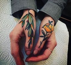 two people with tattoos on their hands holding each other's hands and one is holding an orange