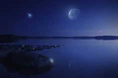 two planets are seen in the night sky over a body of water with rocks on it