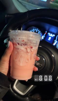 a hand holding a drink in front of a steering wheel with the number 98 on it