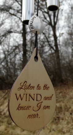 a wind chime hanging from the side of a tree with words written on it