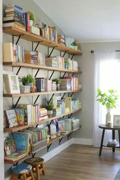 a bookshelf filled with lots of books next to a window