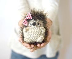 a person holding a small crocheted hedge with a bow on it's head