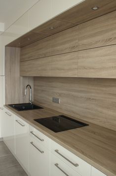 an empty kitchen with white cabinets and wood counter tops on the wall above the sink