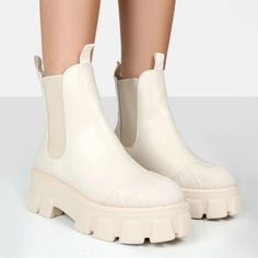 a pair of white boots with chunky soles on the bottom and heeled toes