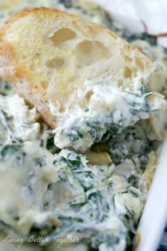 spinach and artichoke dip with garlic bread in a white casserole dish